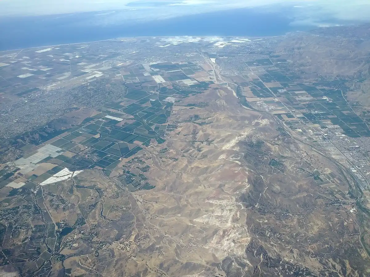 aerial view of farm fields and greenhouses across a coastal plain