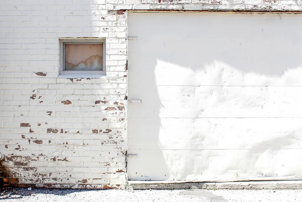 a white garage door in a painted brick wall